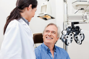 woman eye doctor looking down and smiling at sitting elderly patient