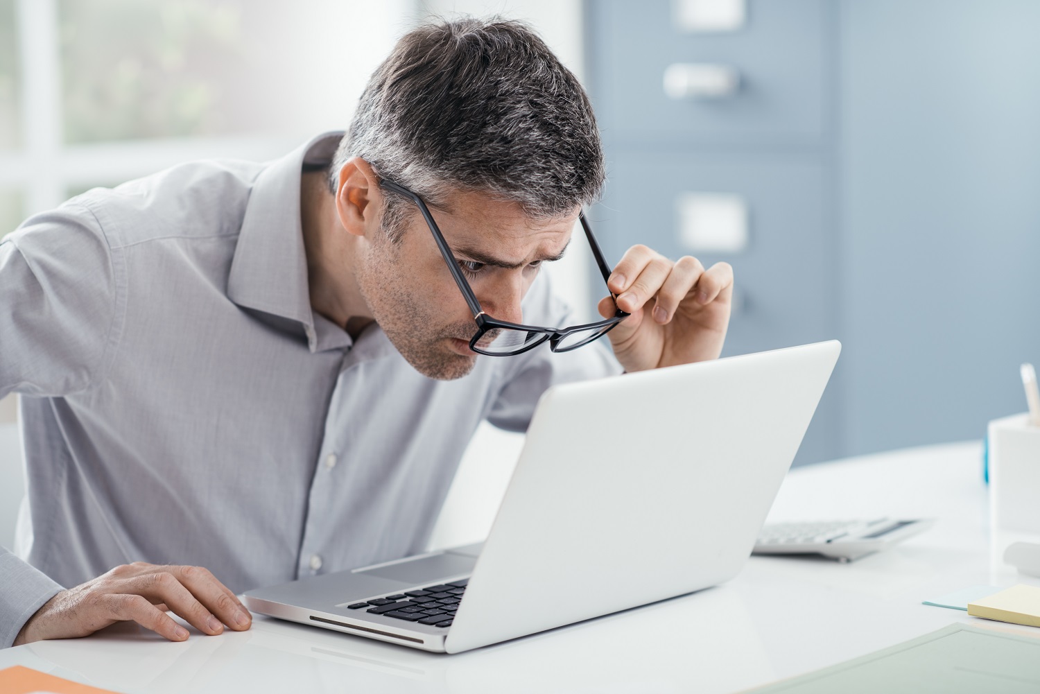 Businessman working at office desk, he is staring at the laptop screen