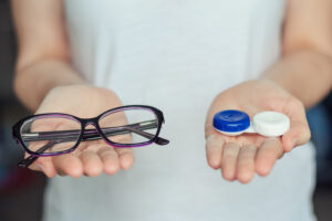 woman hold contact lenses and glasses in hands