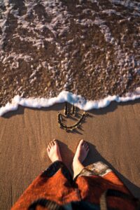 women feet on sand with smiley doodle