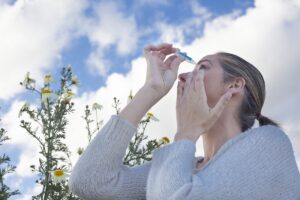 Young woman using eyedropper to treat irritated eyes