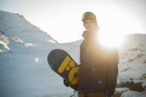 man with snowboard in mountains